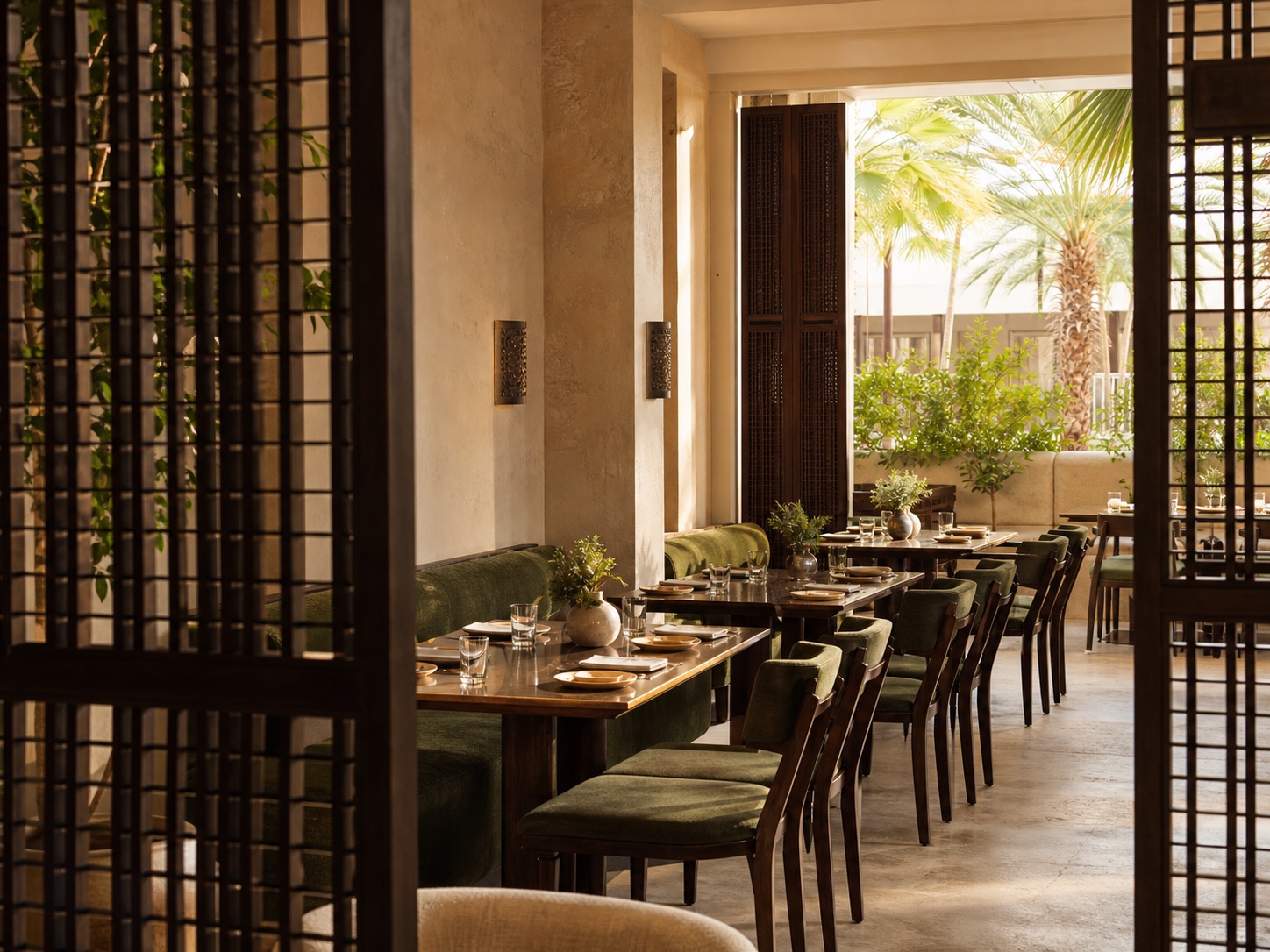 Limestone dining room with palm-green upholstery and warm lighting